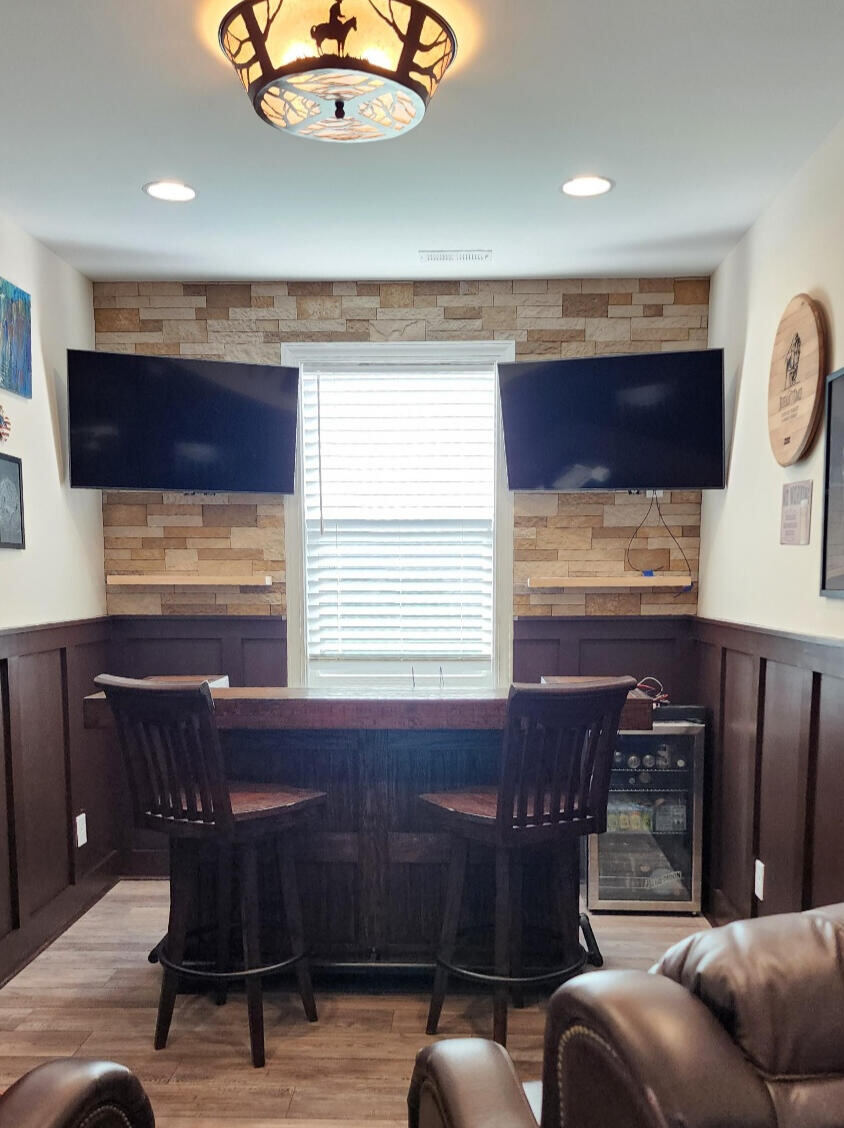 Custom home bar with wall-mounted TVs and stone accent